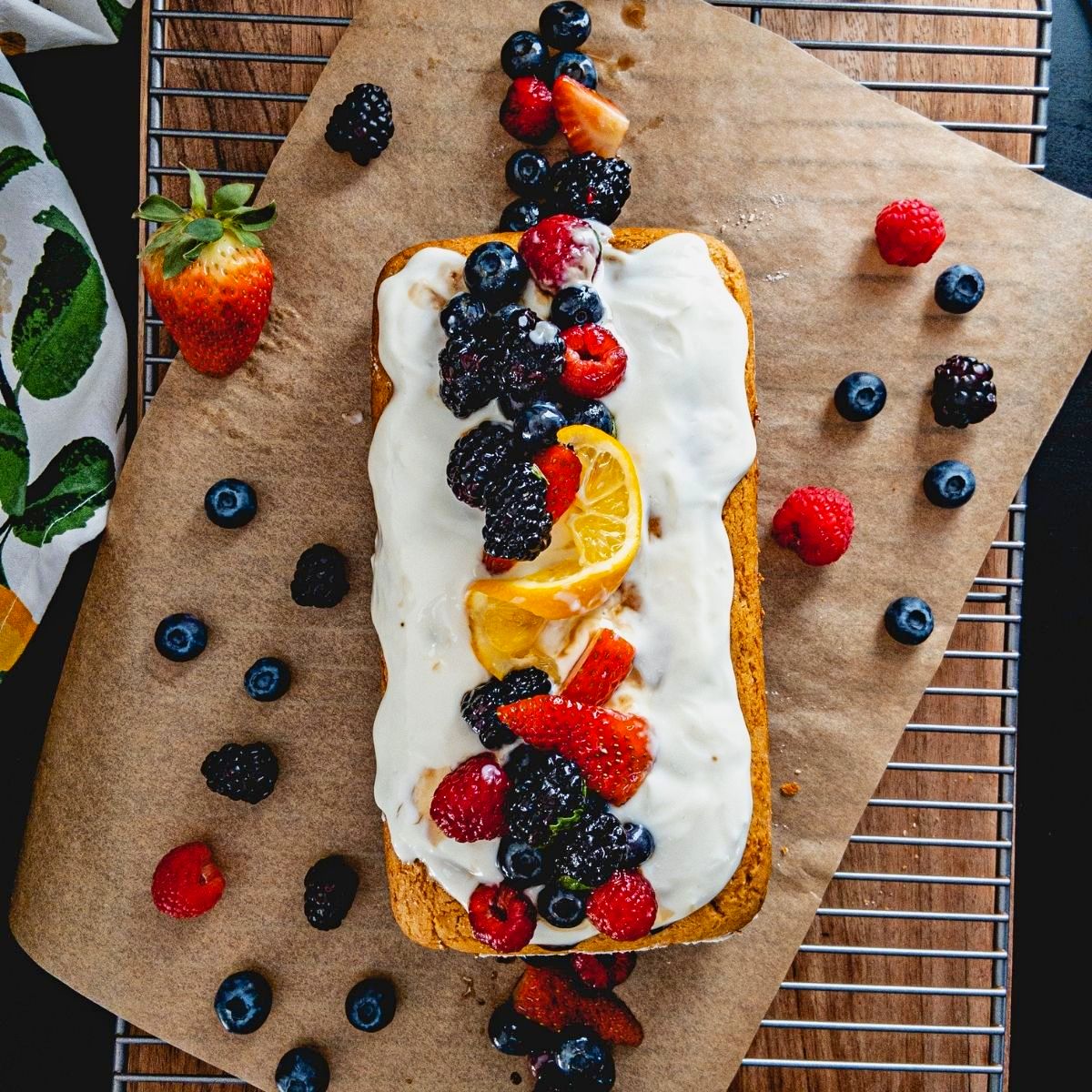 Overview of a lemon cake with white frosting and mixed berries on top.
