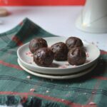 A plate of chocolate balls on a red and green table cloth.