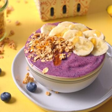 Purple smoothie with bananas and granola on top.