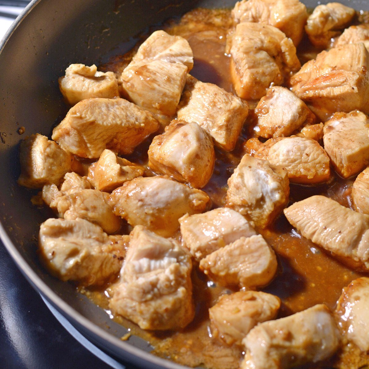 Chicken and teriyaki sauce cooking in a pan after being flipped.