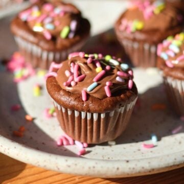 A protein chocolate cupcake with sprinkles on the plate.
