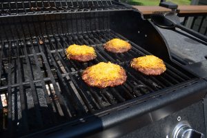 Four cheese burgers on a grill.
