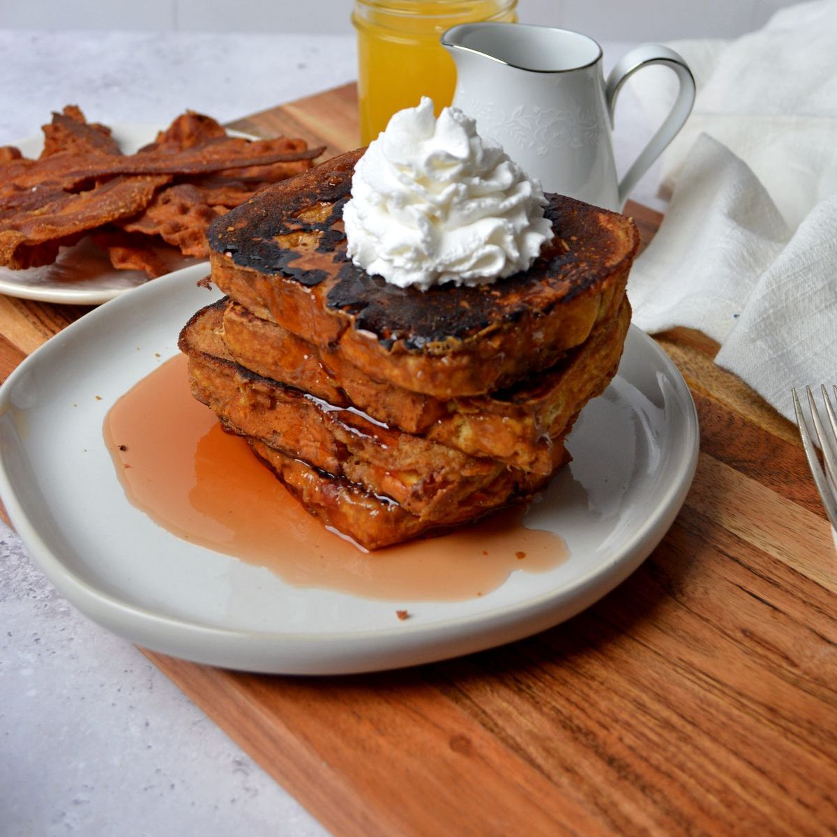 Stack of protein double dip french toast with whipped cream and maple syrup on top