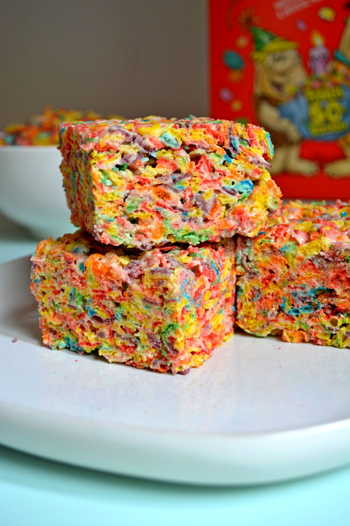 Protein Fruity Pebble Treat Stacked with a box of fruity pebbles in the background