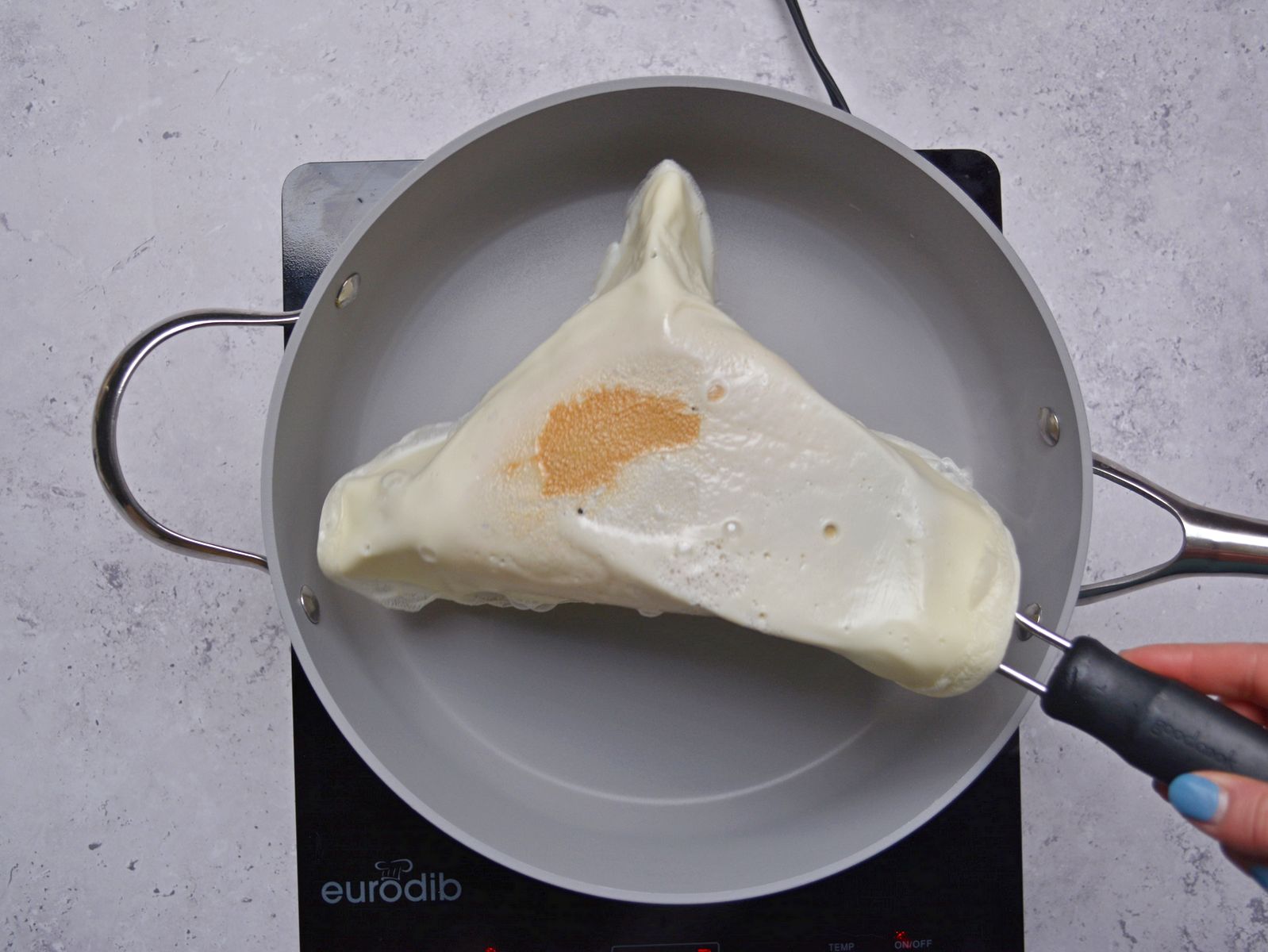 Flipping an egg white wrap in the pan with a spatula.