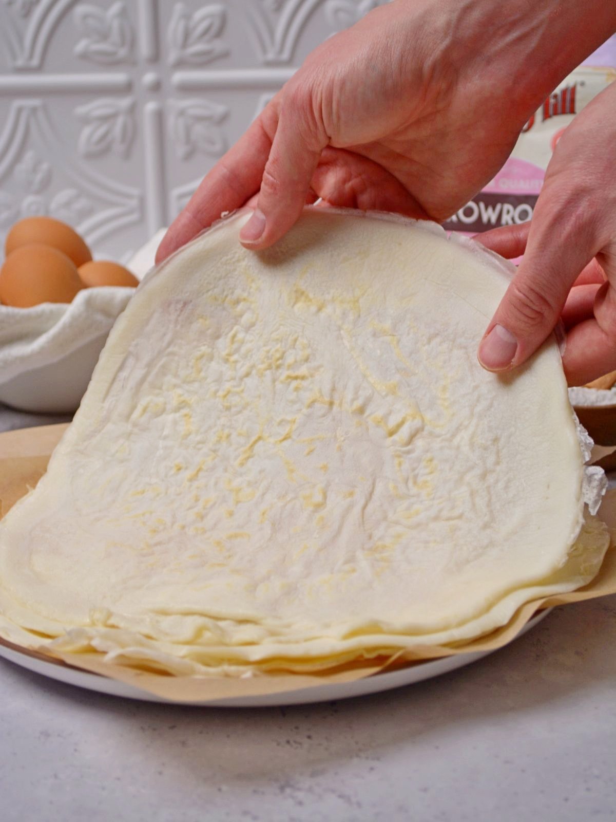 Egg white wraps being lifted by two hands.