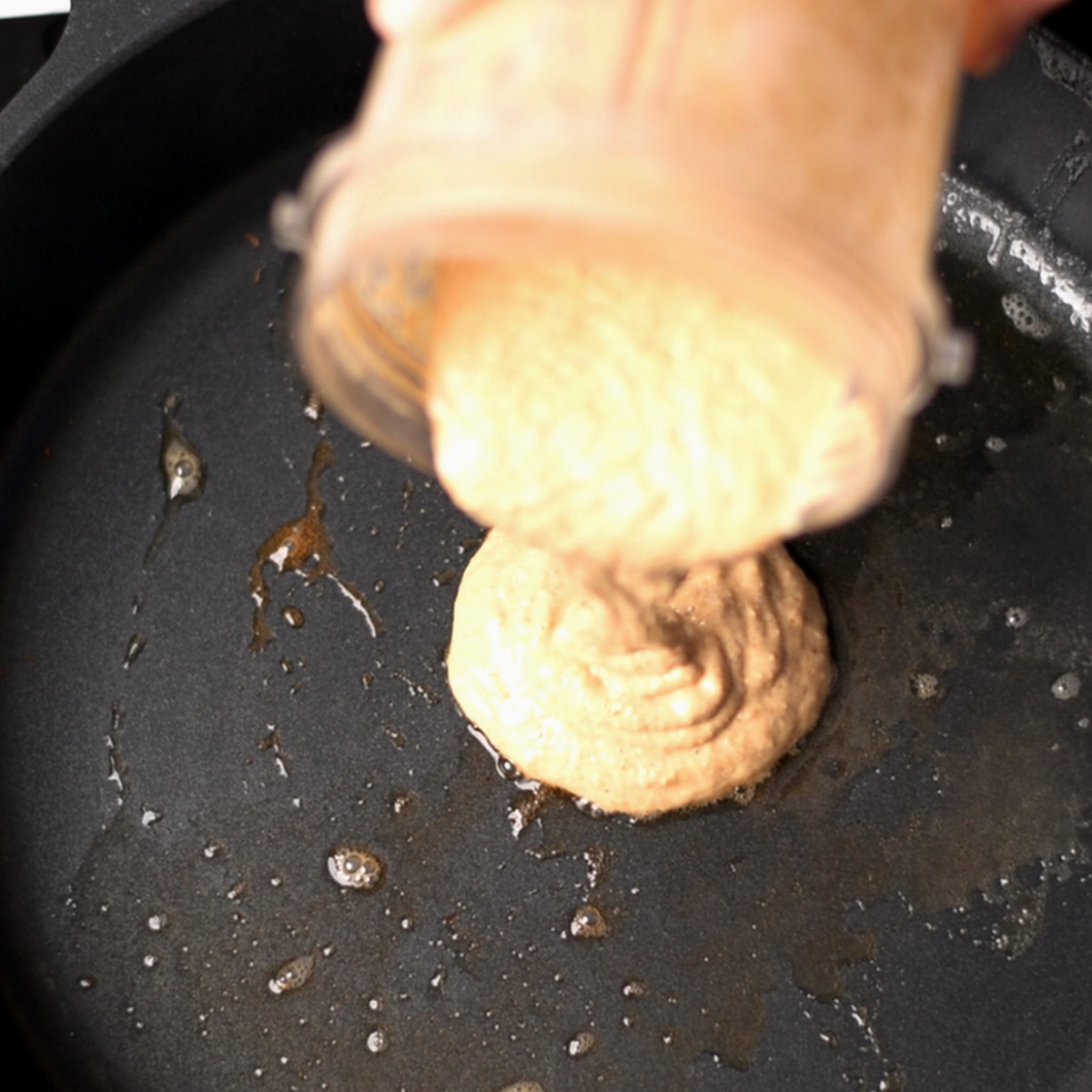 Pouring pancake batter onto a skillet.