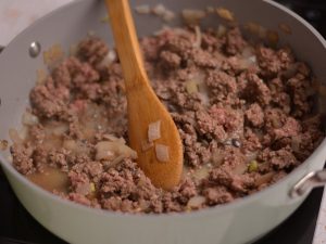 Ground beef being browned in a gray skillet.