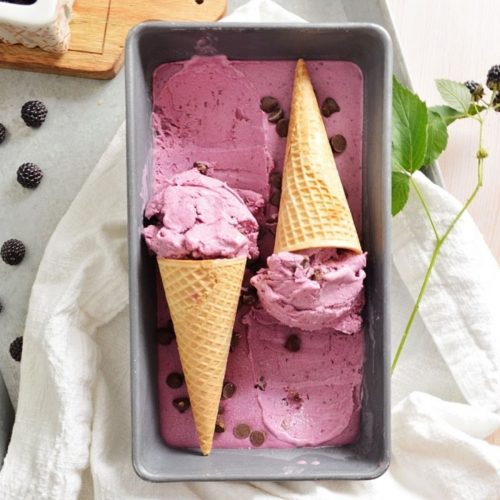 Black raspberry ice cream in a tin with two cones facing opposite ways.