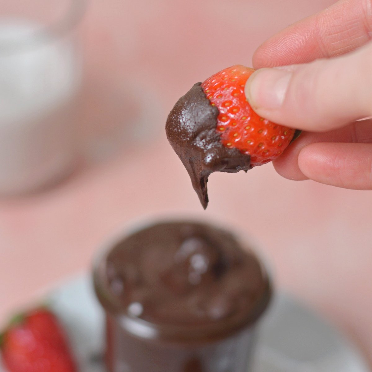A strawberry being dipped into the protein brownie batter.