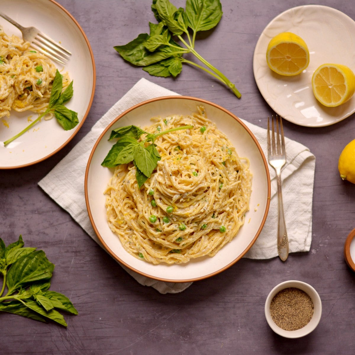 A large plate of spaghetti with a creamy sauce and peas.