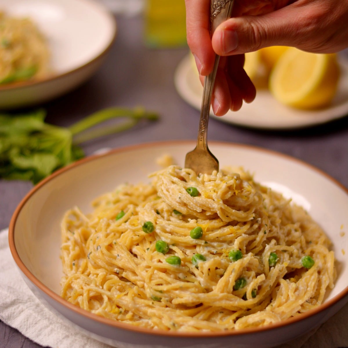 A fork in a pile of spaghetti that has cream sauce and peas on top.