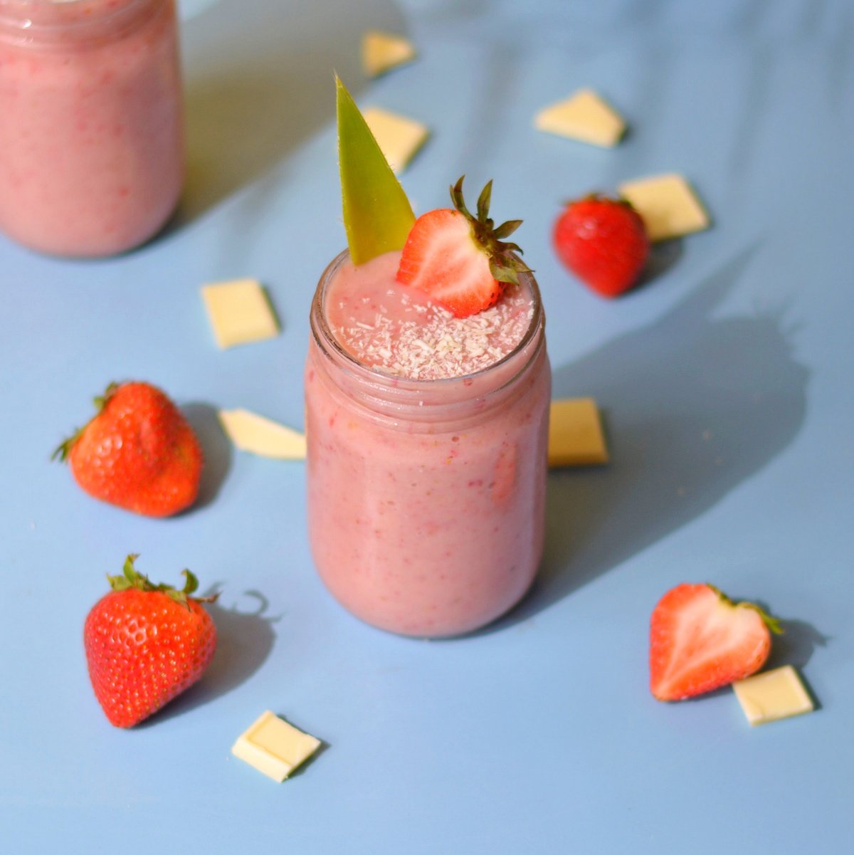 A red smoothie with a strawberry and pineapple leaf on top.