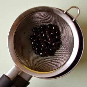 Black boba pearls in a strainer.