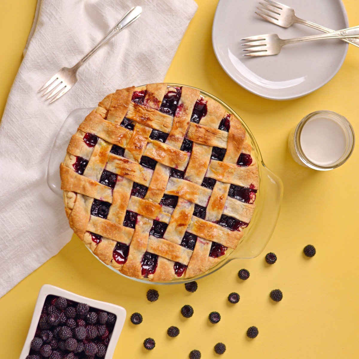 Overhead view of a pie with blackberries next to it.