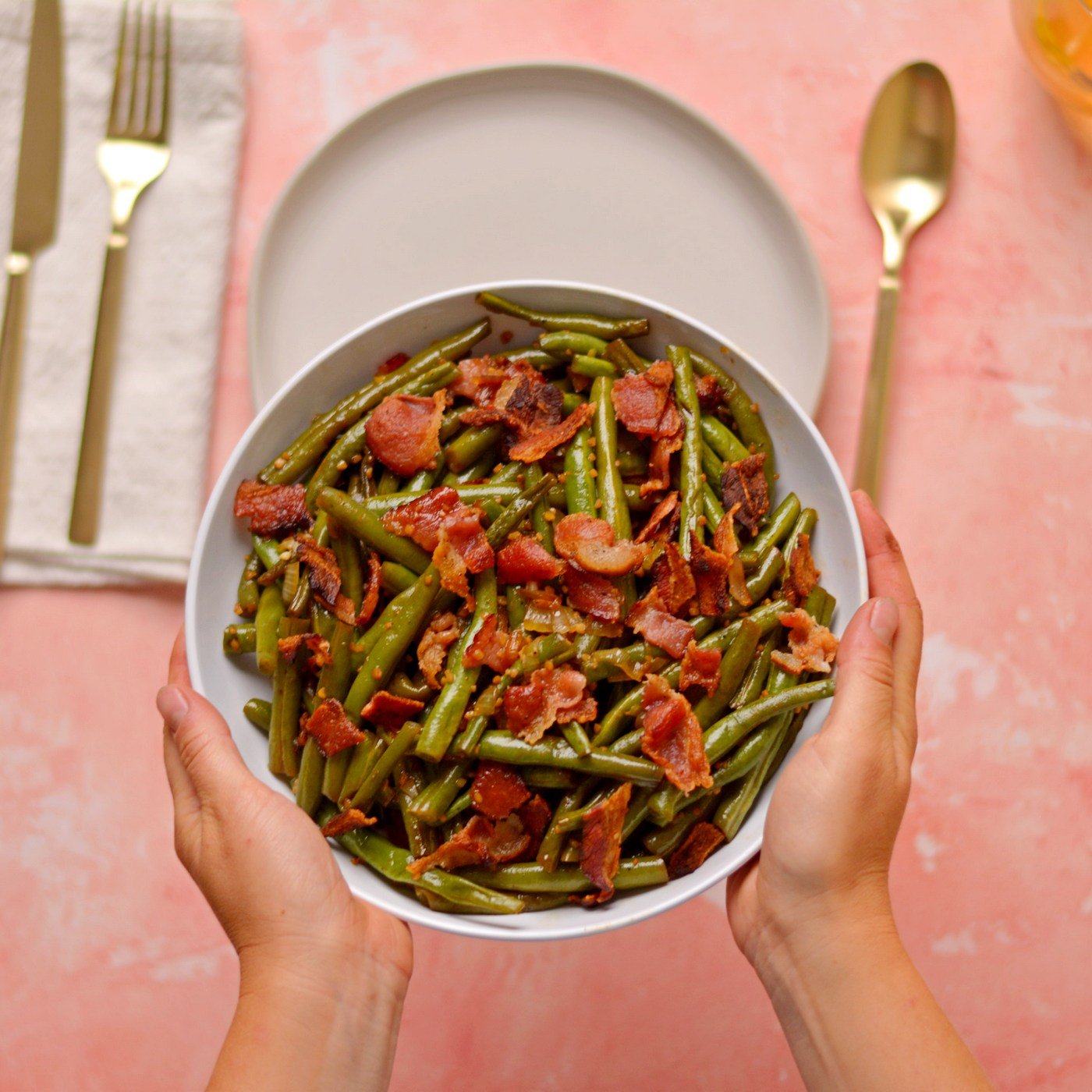 Setting down a bowl of bacon and green beans.