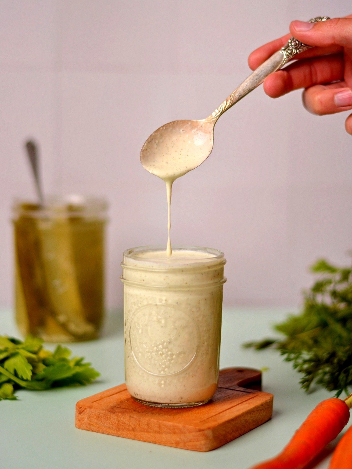 Taking a spoonful of dill pickle dressing from a glass jar.