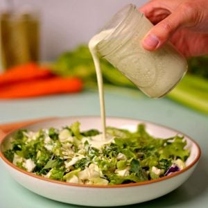 Pouring dressing from a mason jar onto a salad.
