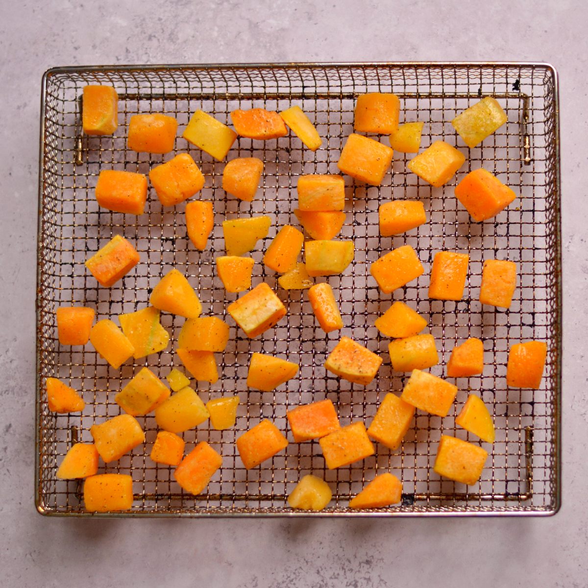 A wire tray with cubes of butternut squash.