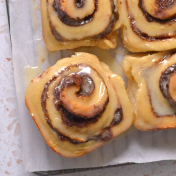 Protein cinnamon rolls next to other cinnamon rolls on parchment paper.