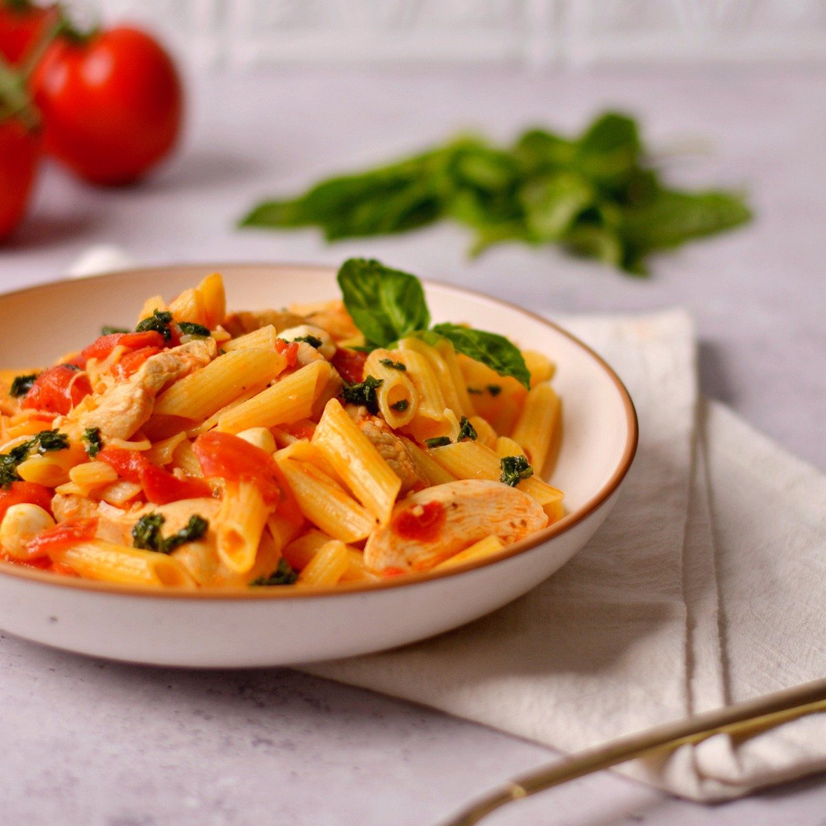 A shallow bowl filled with tomato basil pasta.
