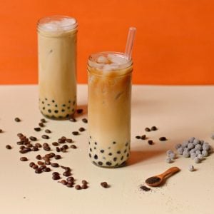 Coffee with milk and boba pears in a tall glass.