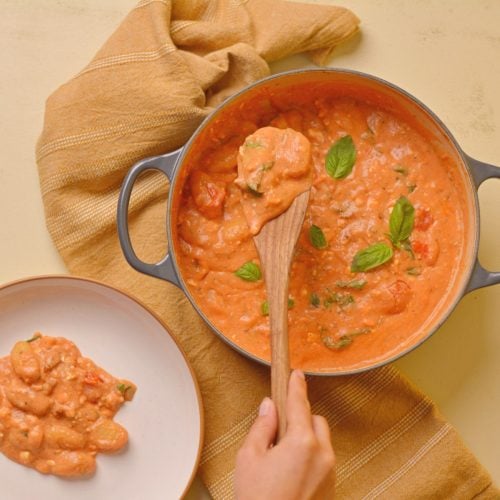 Scooping tomato feta gnocchi out of a pot.