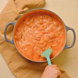 Stirring a pot filled with creamy tomato gnocchi sauce.