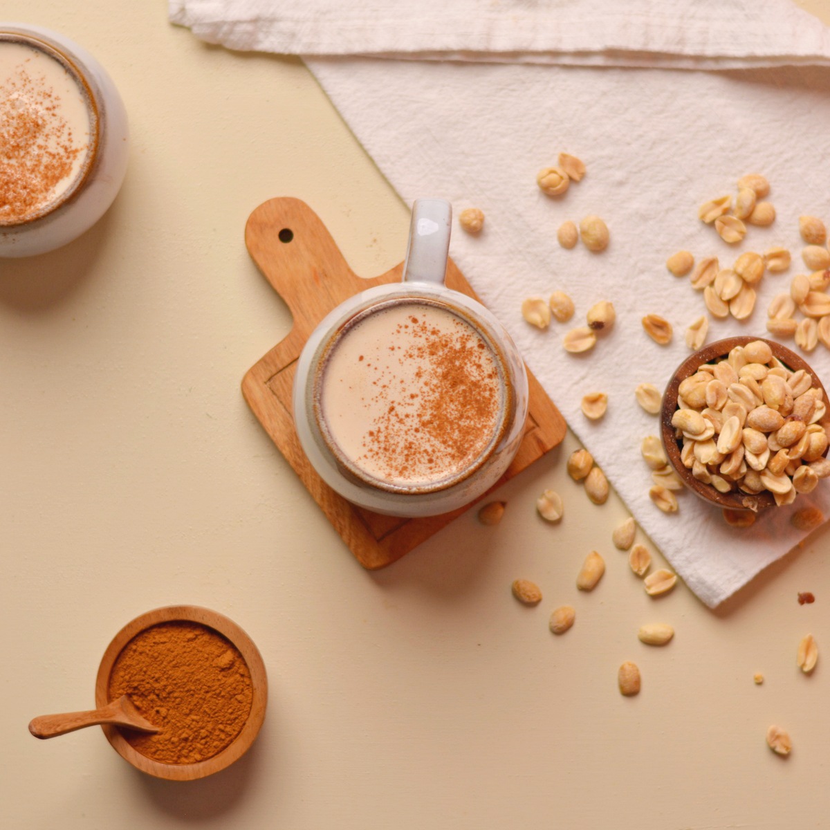 Overhead view of peanut butter latte in a mug with peanuts scattered around.