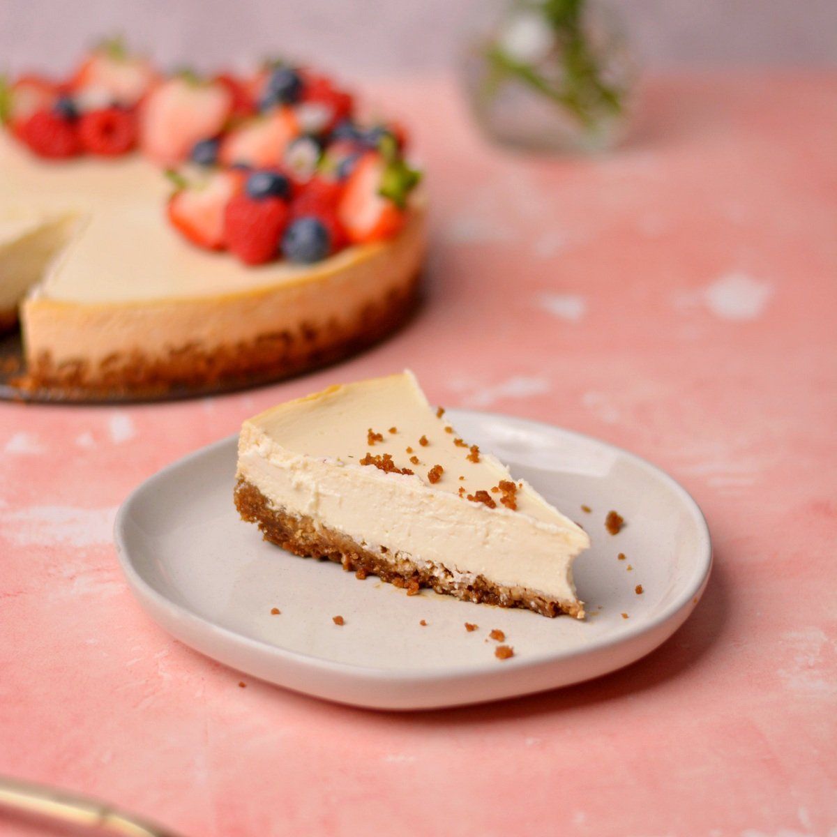 A slice of cheesecake with the full cheesecake in the background.