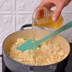 Pouring broth into a Dutch oven with rice.