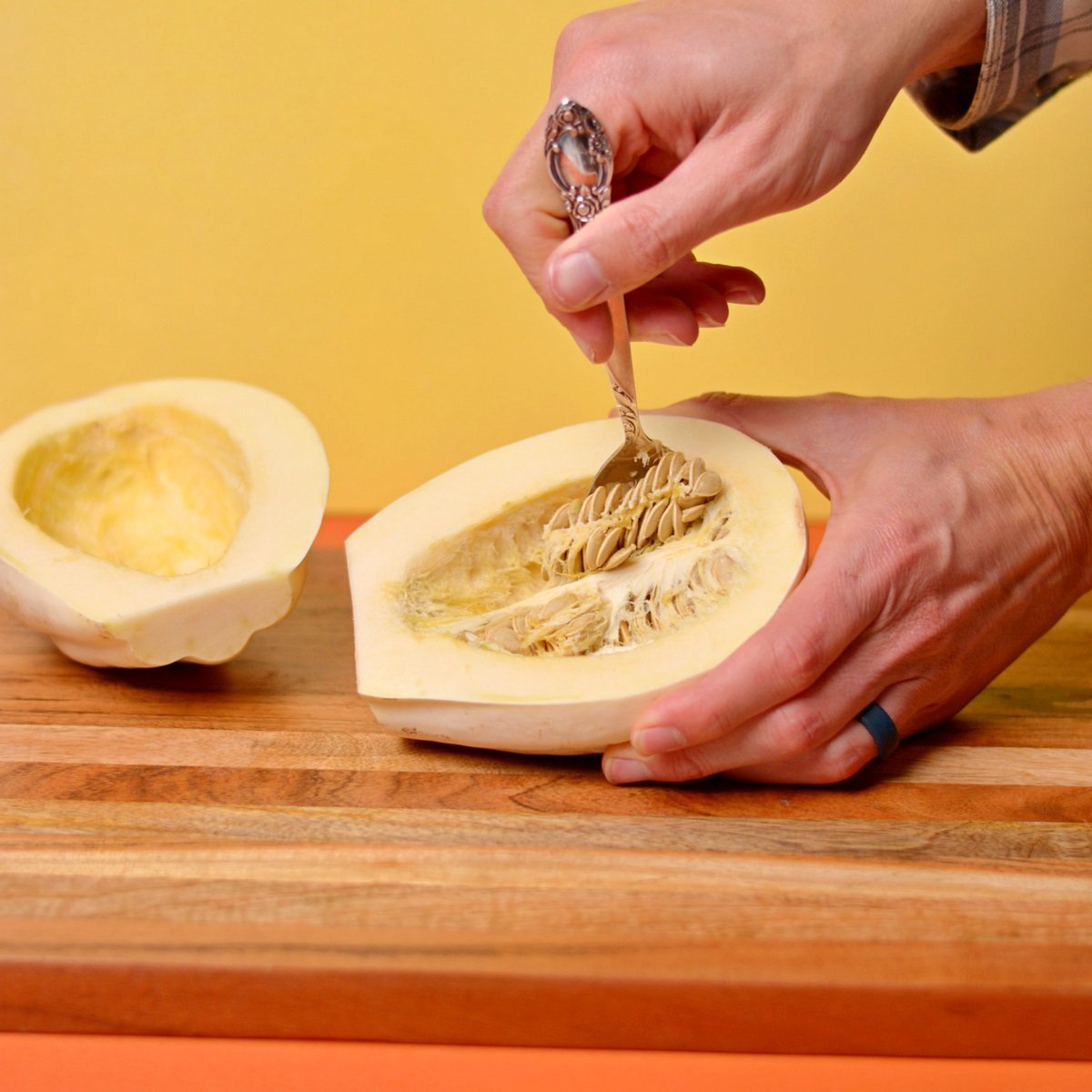 Using a spoon to scoop out seeds from a mashed potato squash.
