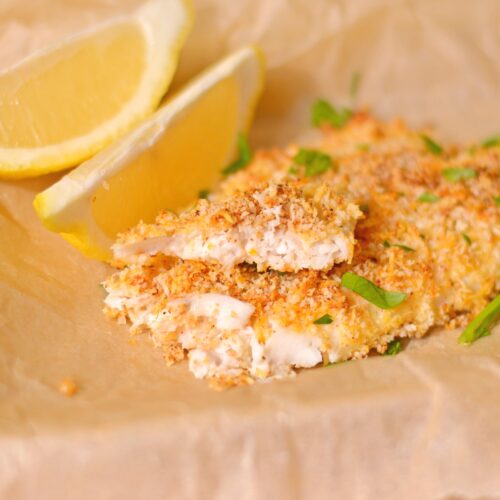 White fish coated in breadcrumbs with chopped parsley on top.