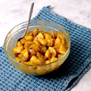 Potato pieces covered in seasoning in a bowl.
