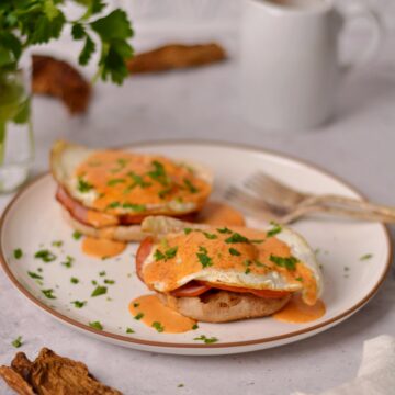 Two eggs benedicts with chipotle hollandaise sauce on top.