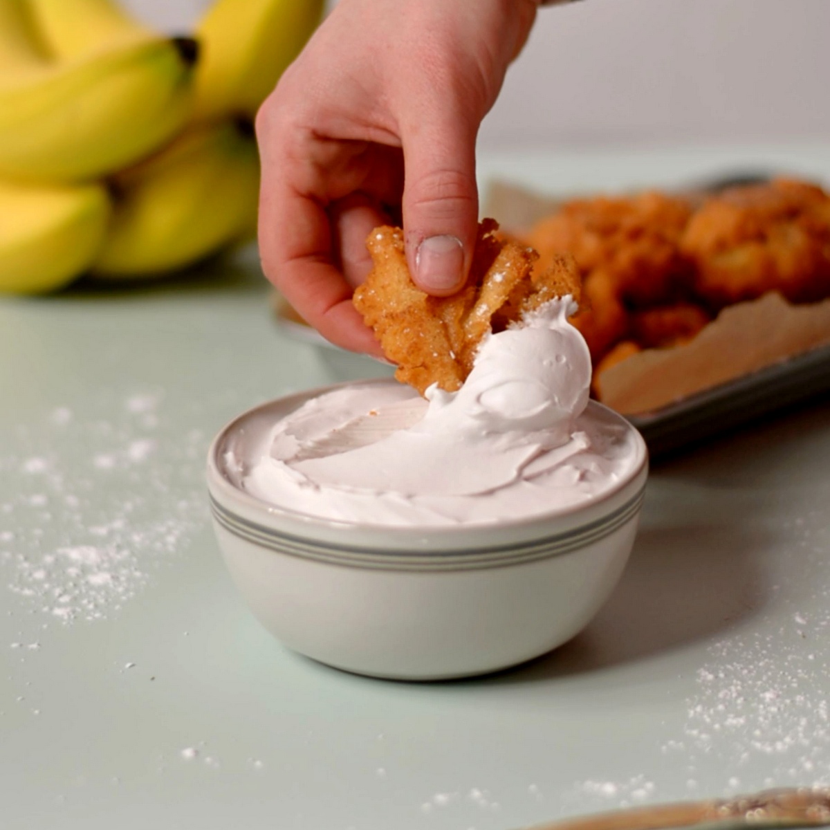 Dipping a fried crispy banana into a coconut cream dip.