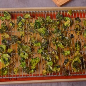 Cooked crispy spinach leaves on a baking tray.