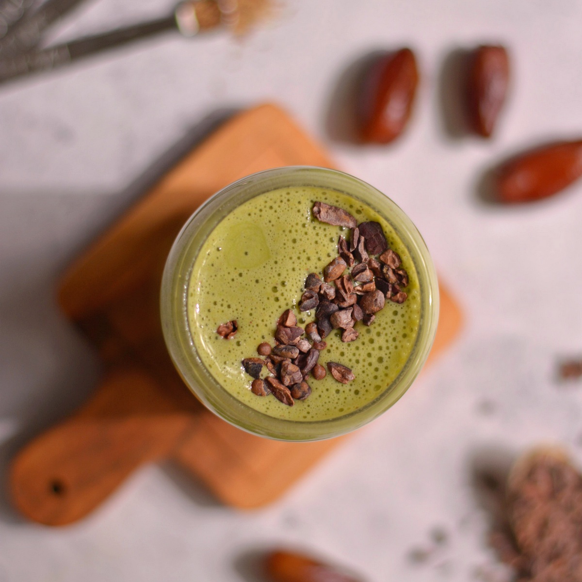 Overhead view of a green shake with cacao nibs on top.