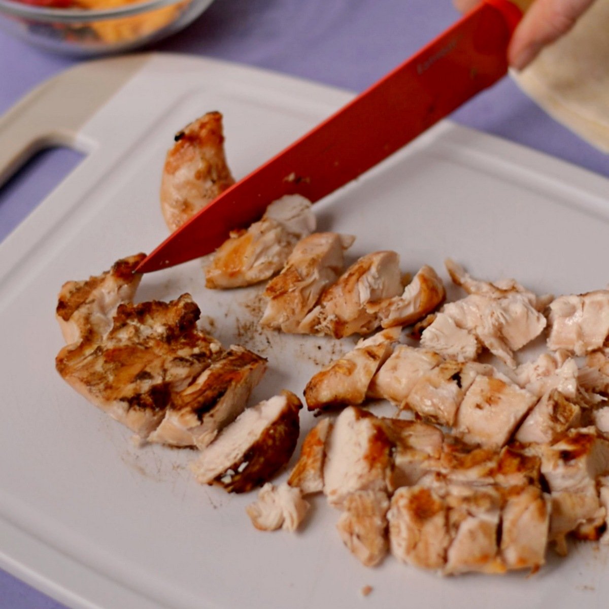 Knife chopping up grilled chicken.