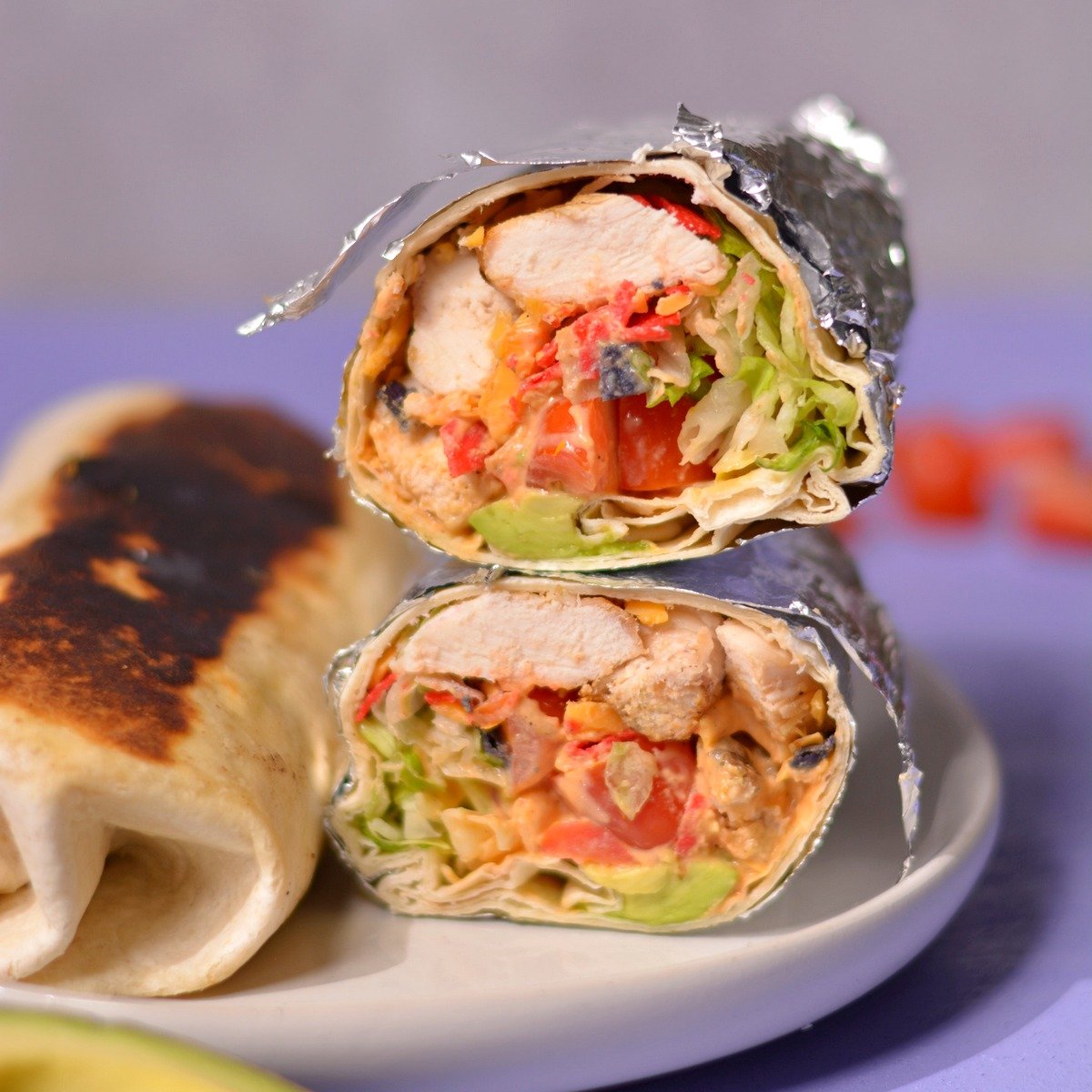 Two burritos side by side, one cut open to show the filling ingredients and one toasted to golden brown.
