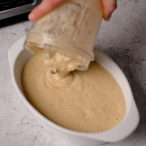 Pouring cookie oatmeal batter into a white ramekin.