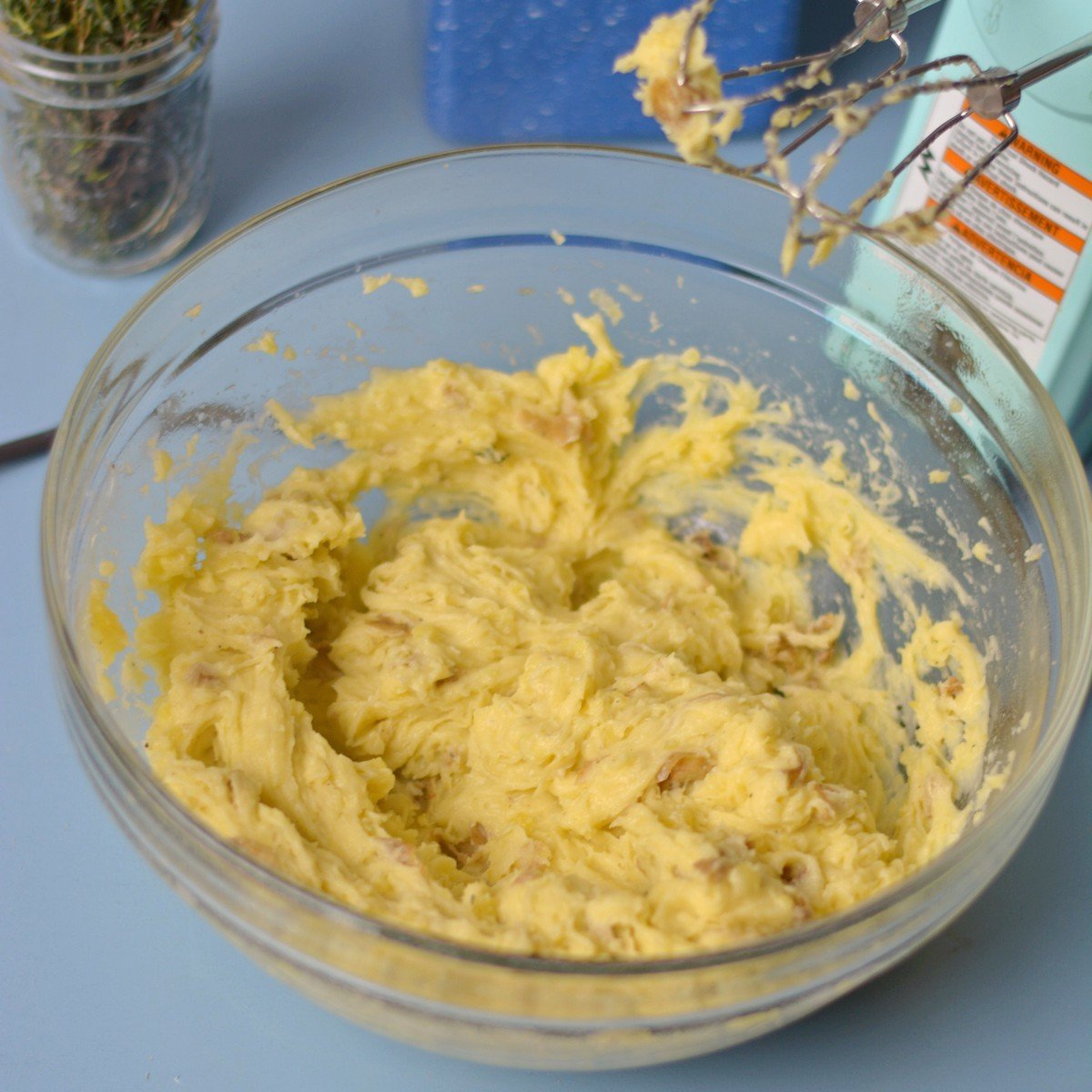 A bowl with potatoes being combined with a hand mixer.