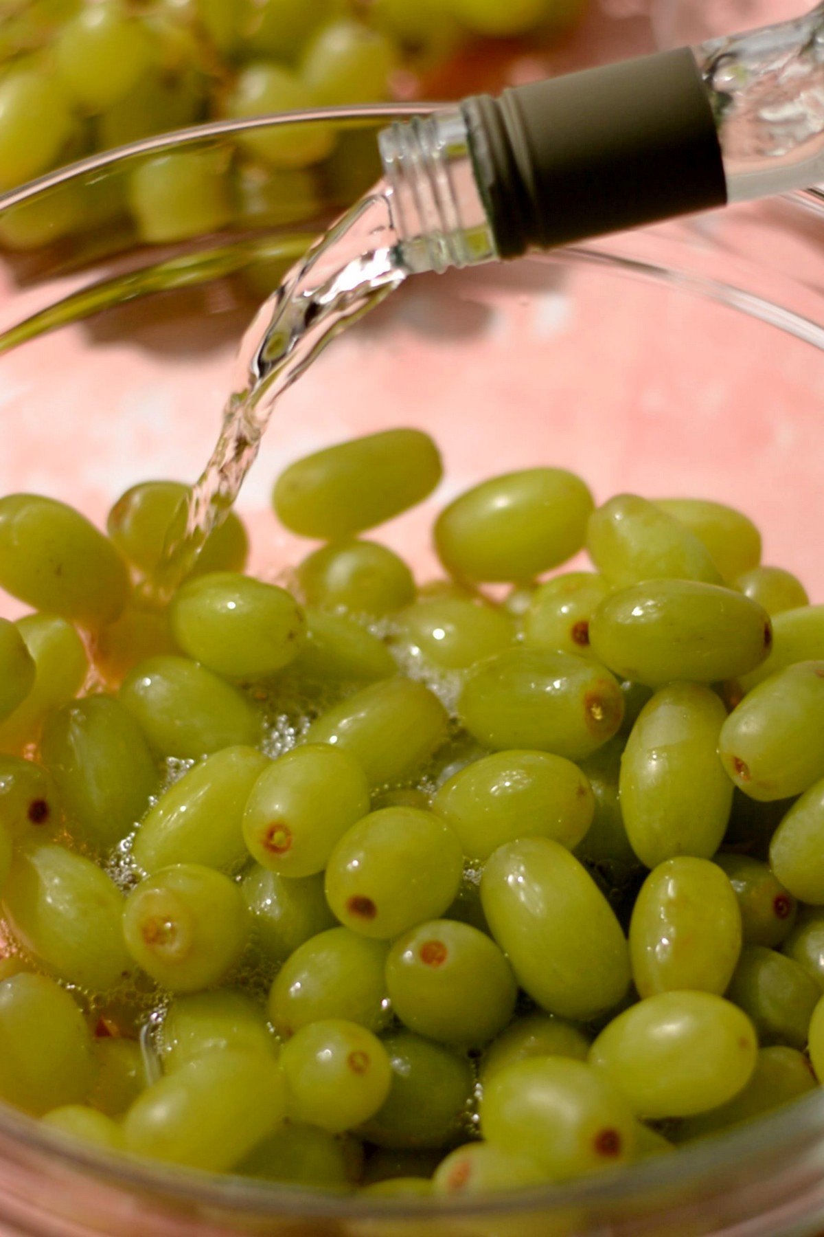 Wine being poured into a bowl of grapes.