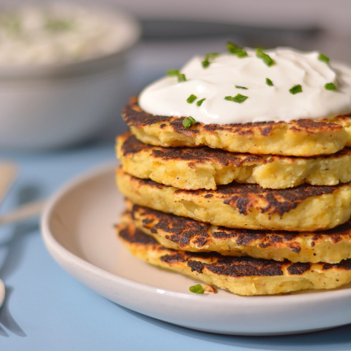 A stack of potato pancakes with sour cream on top.