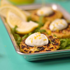 salmon patties on a tray with white sauce and lemons.