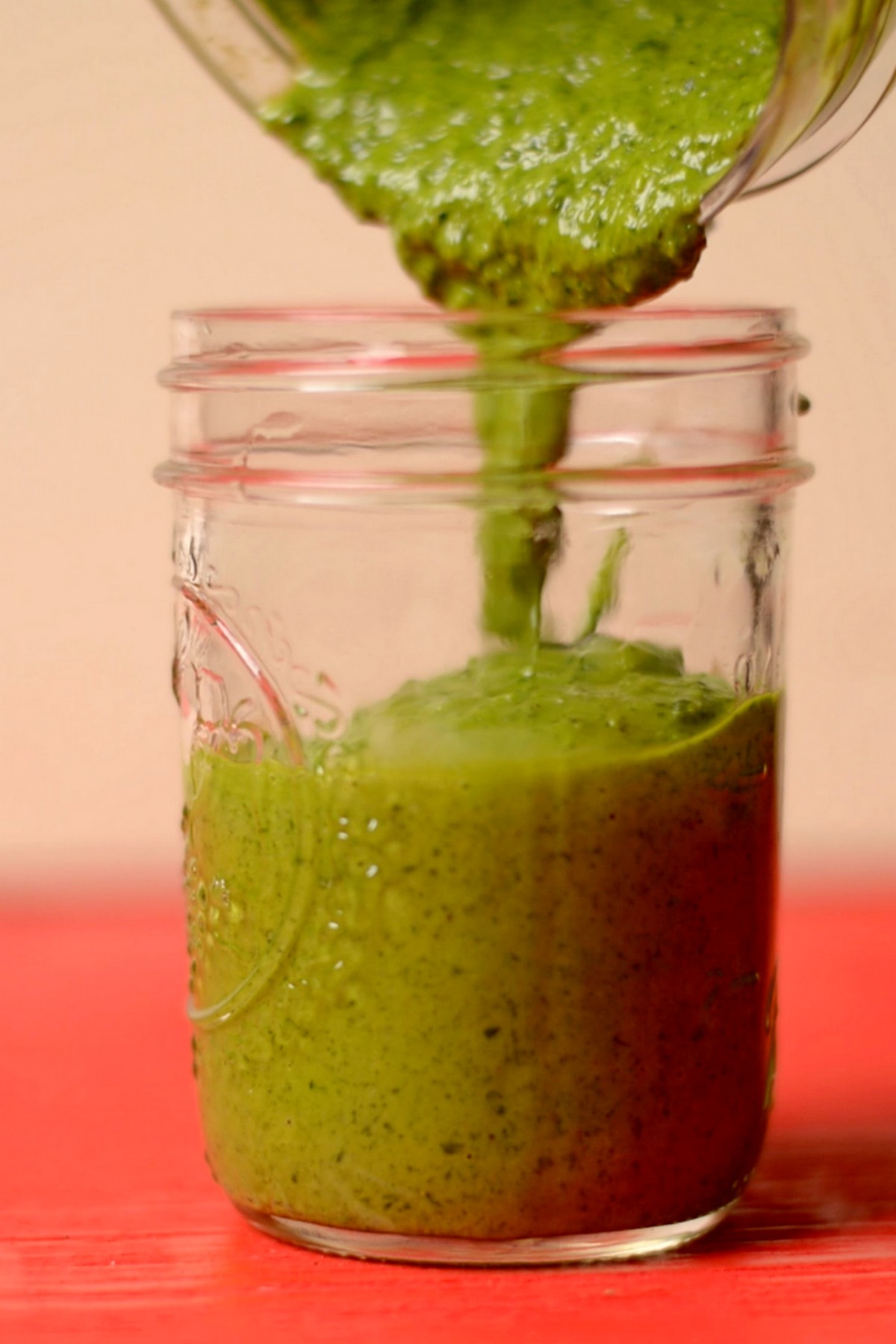 Chimichurri sauce being poured into a glass jar.