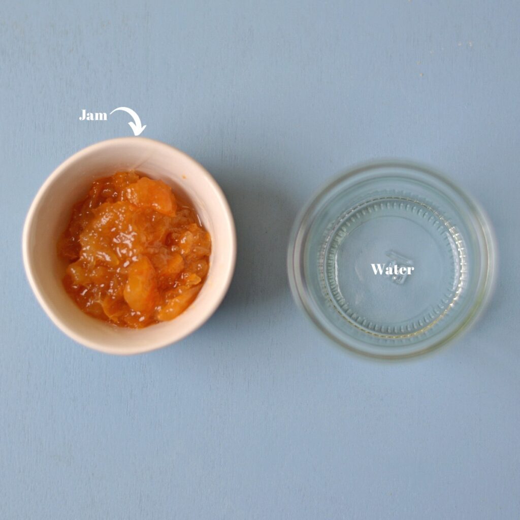 A bowl with apricot jam next to a bowl with water.