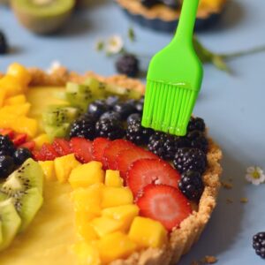 Rubbing glaze on top of fruit on a fruit tart.