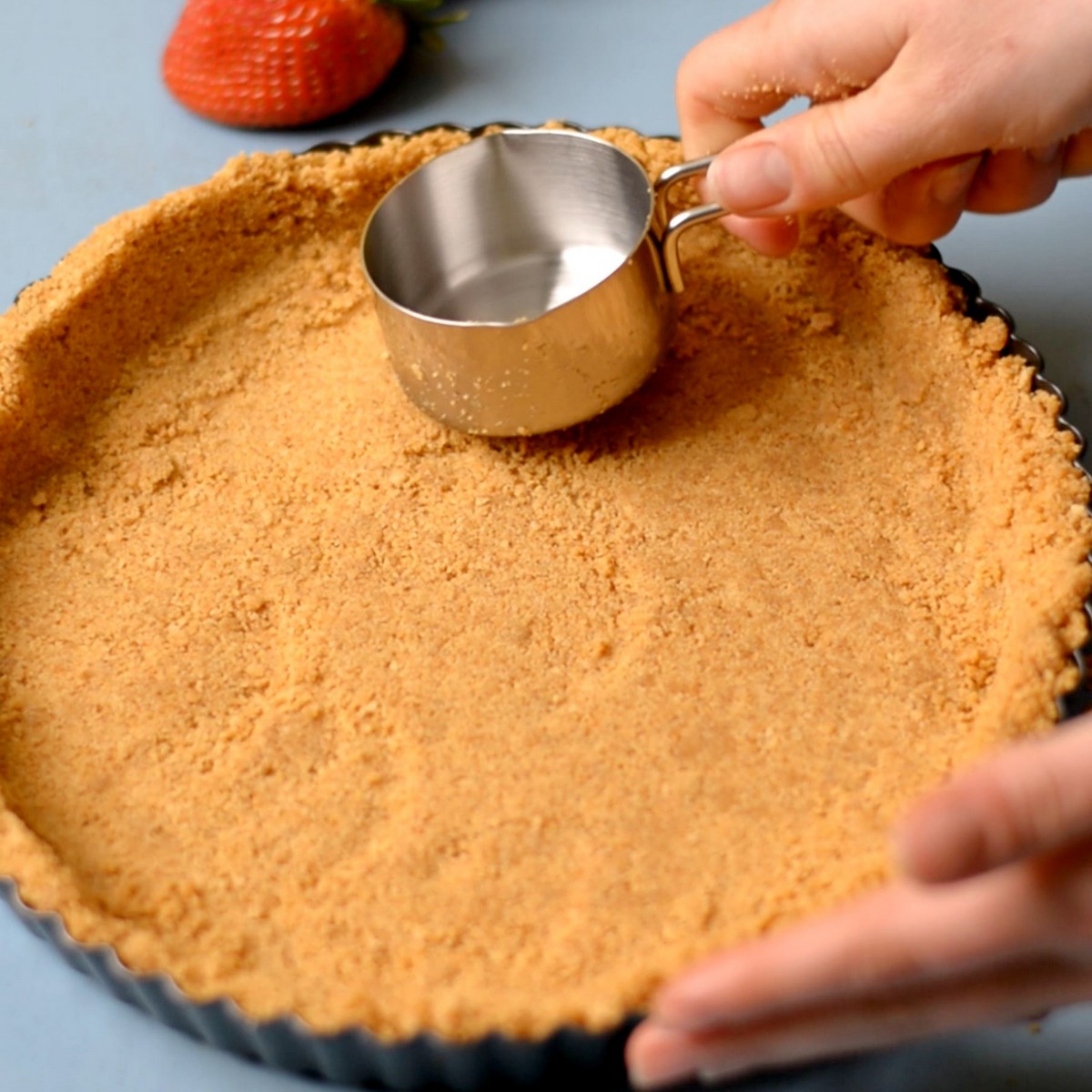 Flattening a graham cracker crust into a pie dish.