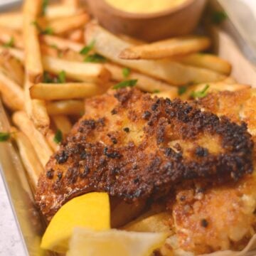 Pan fried walleye and french fries on a tray.